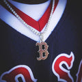Boston Red Sox MLB Logo Pendant in 14k white gold plating with natural red gemstones. Pendant pictured on a 3mm Round Cut Tennis Necklace in White Gold worn by a model in a Boston Red Sox jersey.