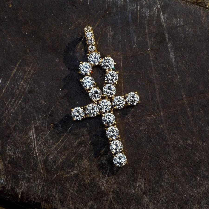 . 3/4 Inch Ankh Cross made up of large CZ stones and yellow gold plated lying flat on a black surface.